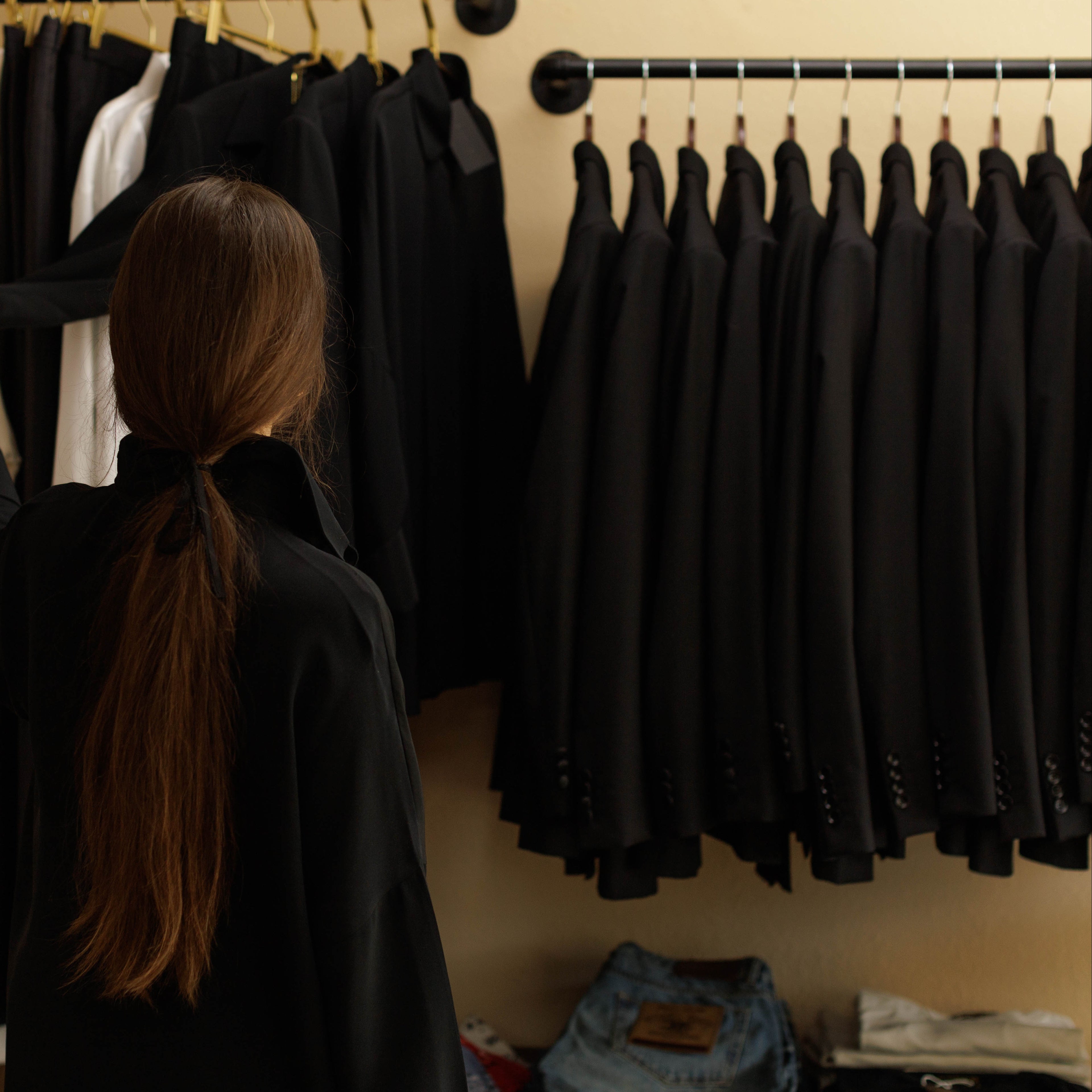 Woman selecting a coat from a rack of clothing in a store.