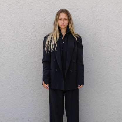 Woma n wearing a  black double breasted silk suit, jacket and pants